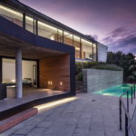 glass house with a swimming pool in the evening on the costa brava